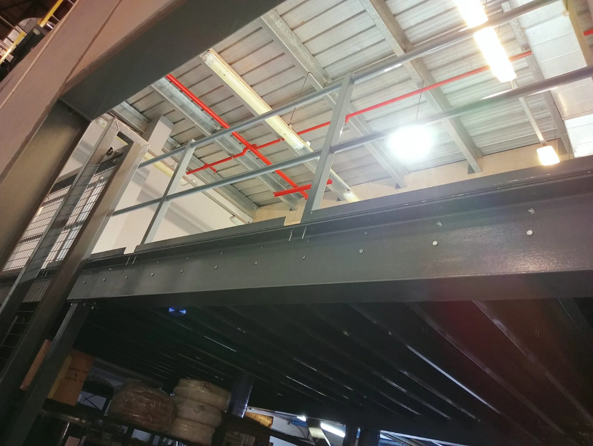 Steel mezzanine beam and handrail beneath a sprinkler main in an engineering plant