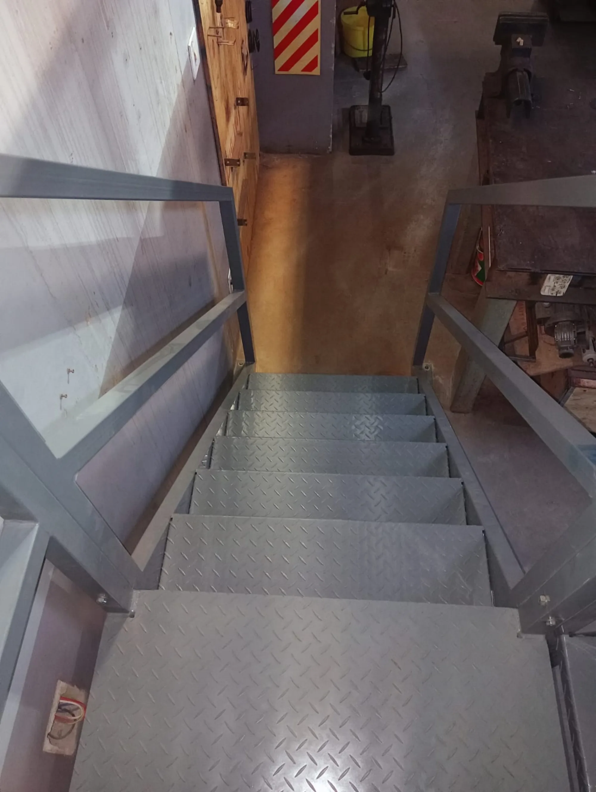 Looking down the mezzanine stair onto the machines on the plant floor